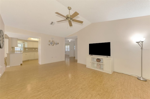 unfurnished living room with ceiling fan, vaulted ceiling, and light wood-type flooring