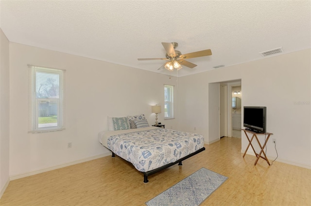 bedroom with a textured ceiling, wood-type flooring, and ceiling fan