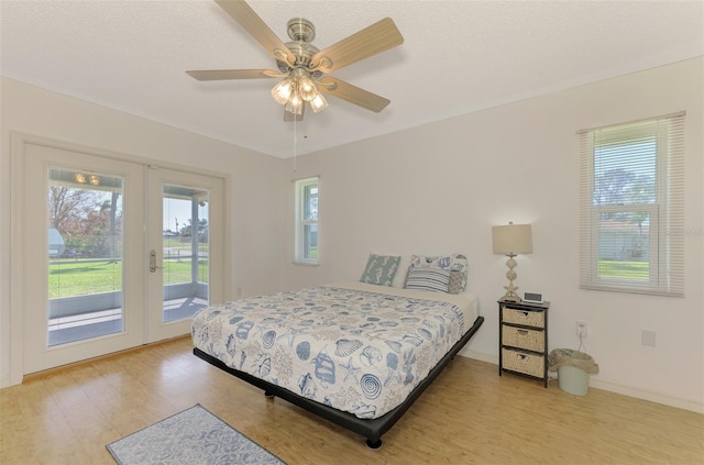 bedroom featuring ceiling fan, wood-type flooring, multiple windows, and access to exterior