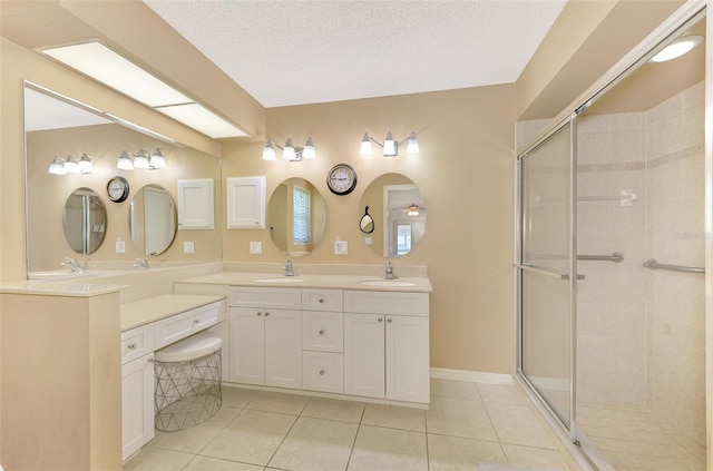 bathroom with vanity, a textured ceiling, tile patterned flooring, and a shower with door