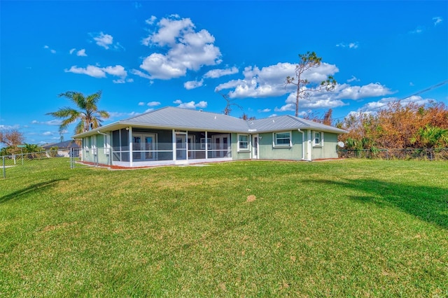 rear view of property featuring a sunroom and a lawn