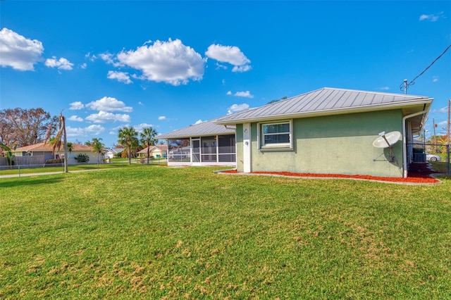 rear view of house featuring a sunroom, central AC, and a lawn