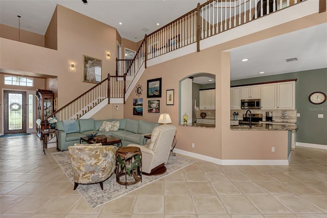 living room featuring sink, a high ceiling, and light tile patterned flooring