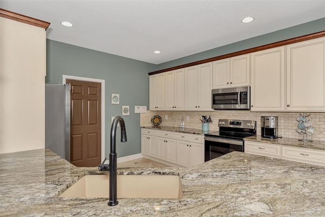 kitchen with light stone countertops, sink, appliances with stainless steel finishes, and decorative backsplash