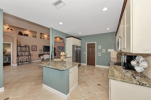 kitchen with light stone countertops, appliances with stainless steel finishes, light tile patterned flooring, and tasteful backsplash