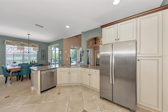 kitchen featuring light stone countertops, appliances with stainless steel finishes, pendant lighting, a notable chandelier, and light tile patterned floors