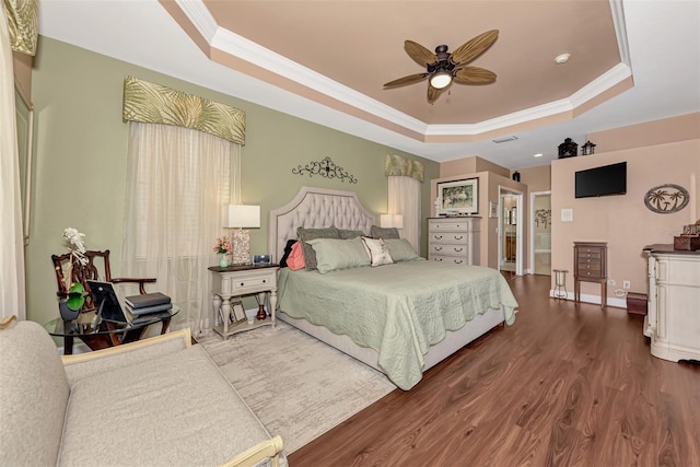 bedroom with crown molding, dark wood-type flooring, a tray ceiling, and ceiling fan