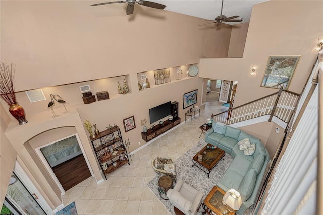 living room with ceiling fan and a towering ceiling