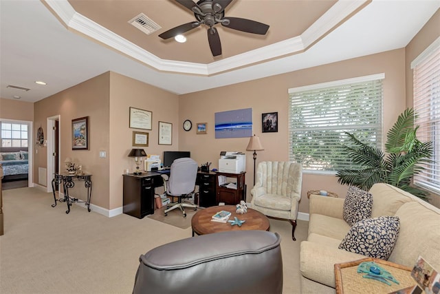 office featuring crown molding, light colored carpet, a tray ceiling, and ceiling fan