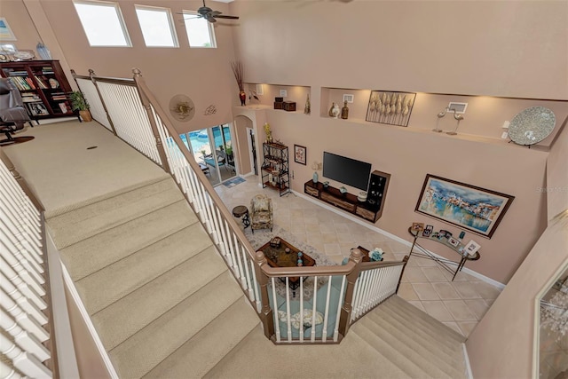 stairs featuring a high ceiling, a barn door, tile patterned flooring, and ceiling fan