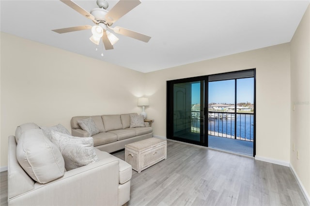 living room with a water view, light wood-type flooring, and ceiling fan