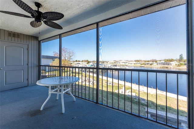 unfurnished sunroom with a water view and ceiling fan