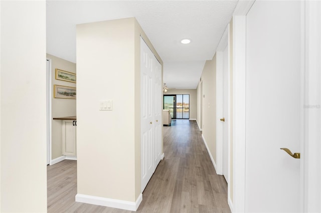 hall with light hardwood / wood-style floors and a textured ceiling