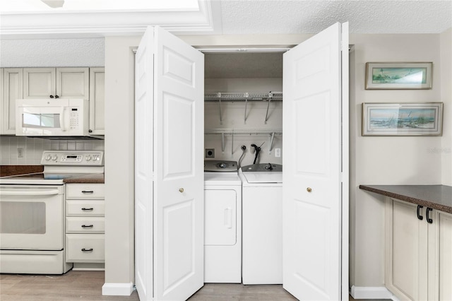 washroom featuring a textured ceiling, washing machine and dryer, and light hardwood / wood-style floors