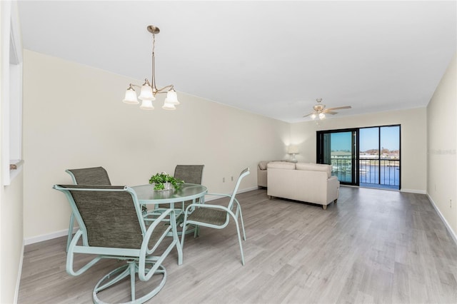 dining space with light hardwood / wood-style flooring and ceiling fan with notable chandelier