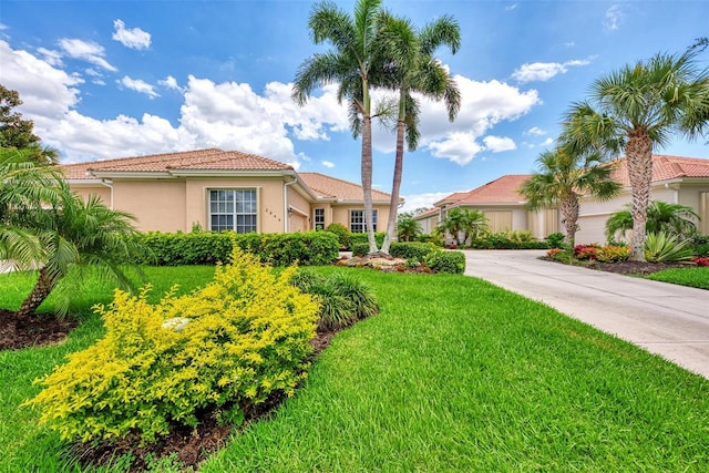 mediterranean / spanish-style house featuring stucco siding, a tile roof, and a front yard