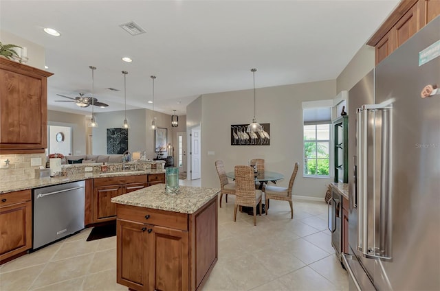 kitchen featuring decorative backsplash, light stone counters, appliances with stainless steel finishes, pendant lighting, and sink