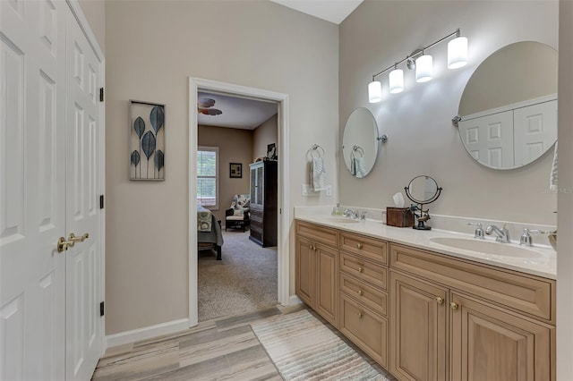 ensuite bathroom with double vanity, a sink, baseboards, and connected bathroom