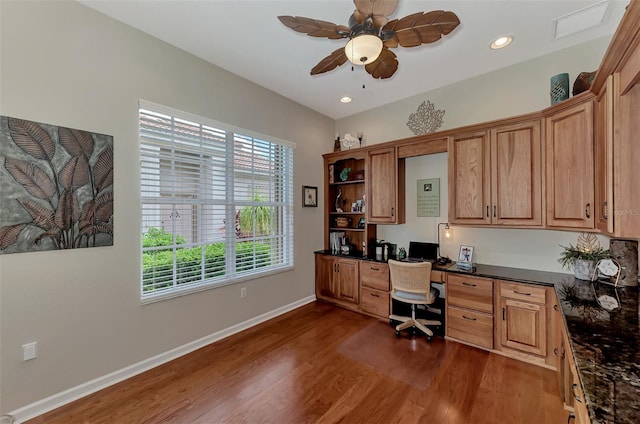 home office with built in desk, ceiling fan, and dark hardwood / wood-style flooring