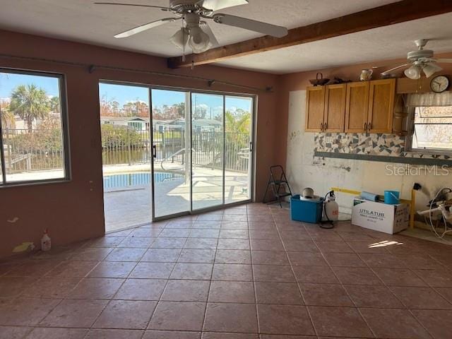 kitchen featuring tile patterned floors, ceiling fan, beamed ceiling, and a healthy amount of sunlight