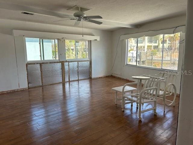 unfurnished room featuring ceiling fan, a healthy amount of sunlight, and dark hardwood / wood-style flooring