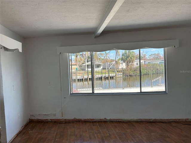 unfurnished room with beam ceiling, a water view, wood-type flooring, and a textured ceiling