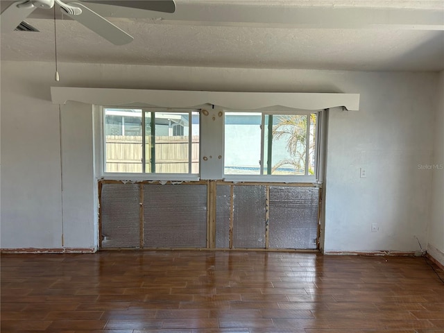 spare room with a healthy amount of sunlight, ceiling fan, dark wood-type flooring, and a textured ceiling