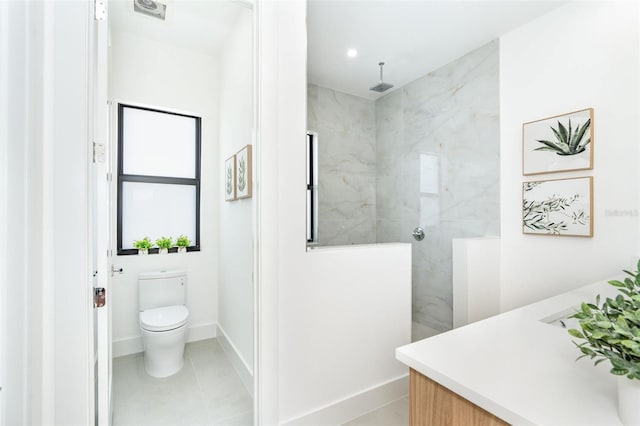 bathroom with vanity, tiled shower, toilet, and tile patterned floors