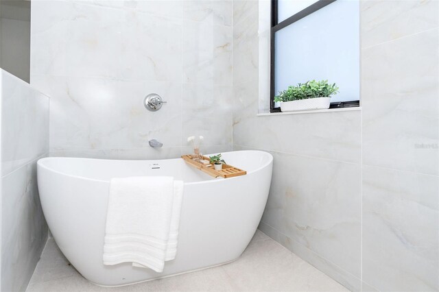 bathroom featuring tile walls, tile patterned flooring, and a washtub