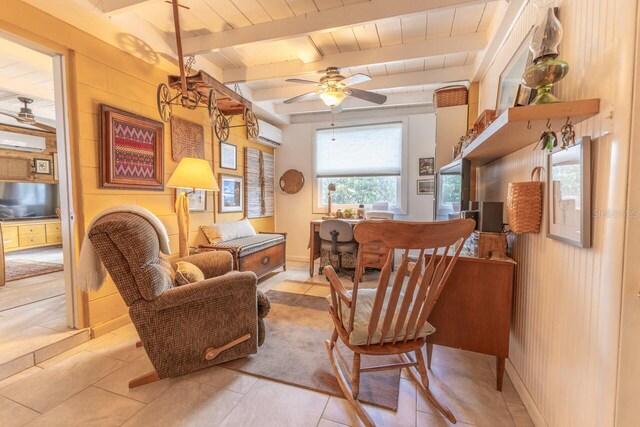 sitting room featuring light tile patterned floors, a wall mounted AC, and beamed ceiling