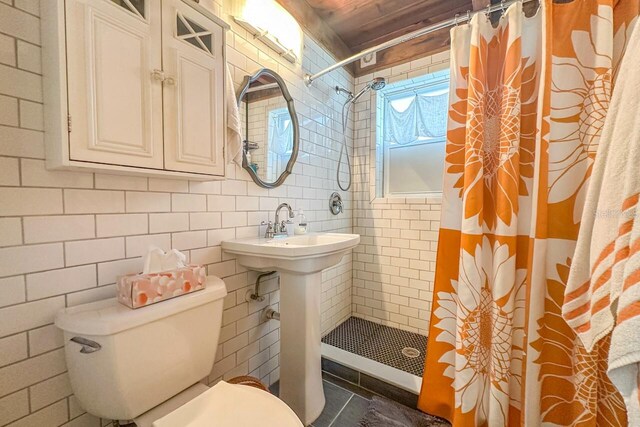 bathroom with toilet, a shower with curtain, and tile walls