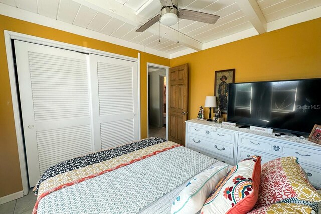 bedroom featuring wooden ceiling, beamed ceiling, a closet, and ceiling fan