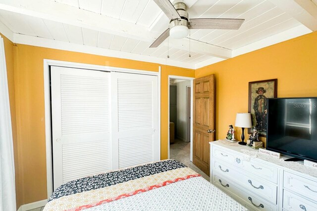 bedroom with a closet, beamed ceiling, wooden ceiling, and ceiling fan