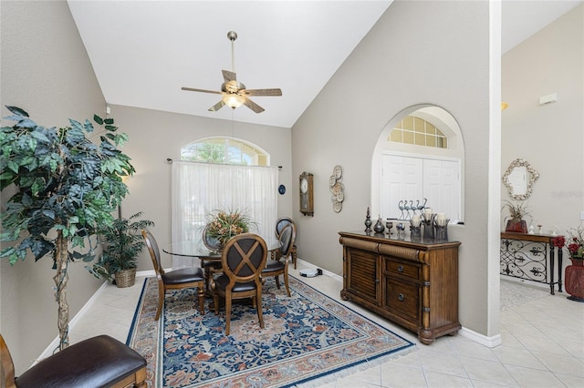 tiled dining space featuring ceiling fan and high vaulted ceiling