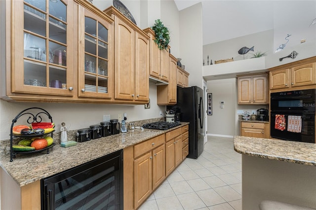 kitchen with black appliances, light stone countertops, light tile patterned floors, and beverage cooler