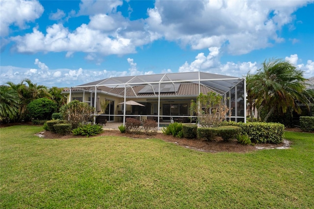 rear view of property with a lawn and glass enclosure