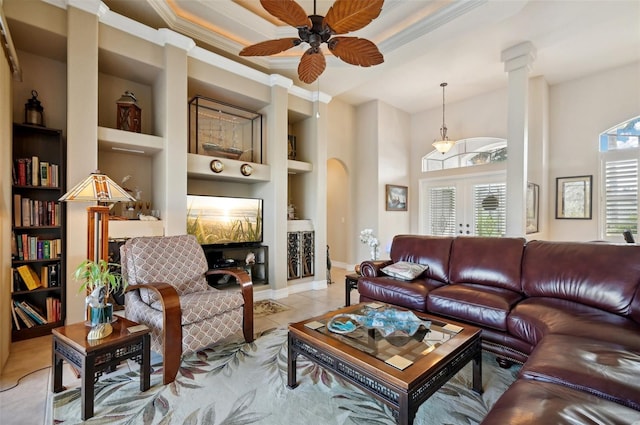 tiled living room featuring built in shelves, ornate columns, ceiling fan, and crown molding