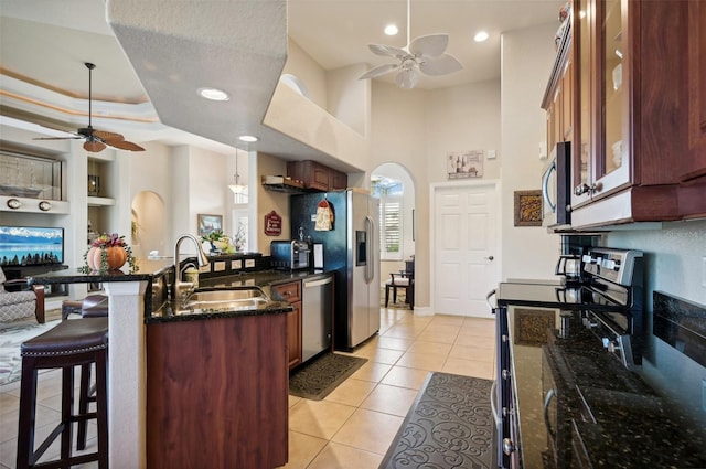 kitchen with ceiling fan, sink, a breakfast bar area, light tile patterned floors, and appliances with stainless steel finishes