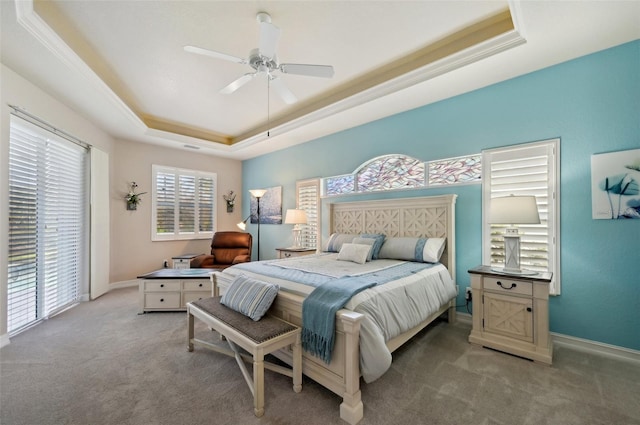 carpeted bedroom featuring ceiling fan, a raised ceiling, and ornamental molding