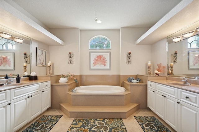 bathroom featuring tile patterned flooring, vanity, a wealth of natural light, and tiled tub