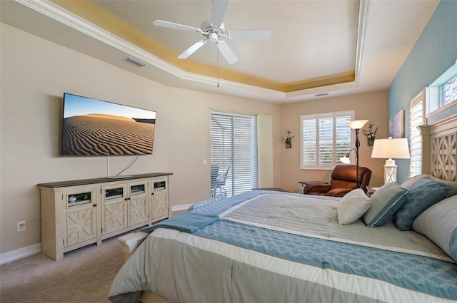 carpeted bedroom featuring a tray ceiling, multiple windows, and ceiling fan