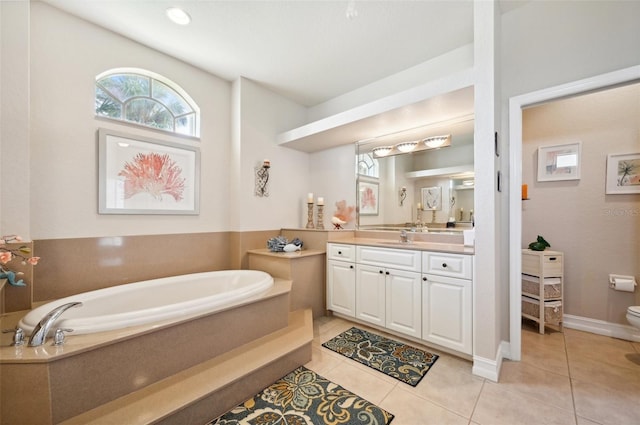 bathroom featuring tile patterned flooring, vanity, a relaxing tiled tub, and toilet