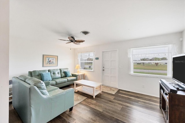 living room featuring dark wood-type flooring, a healthy amount of sunlight, and ceiling fan