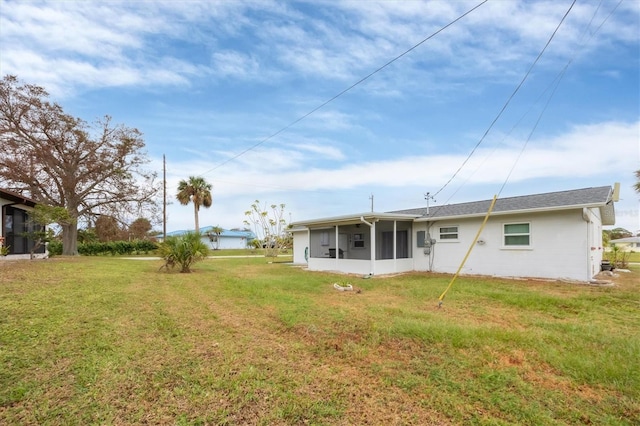 rear view of house featuring a yard and a sunroom