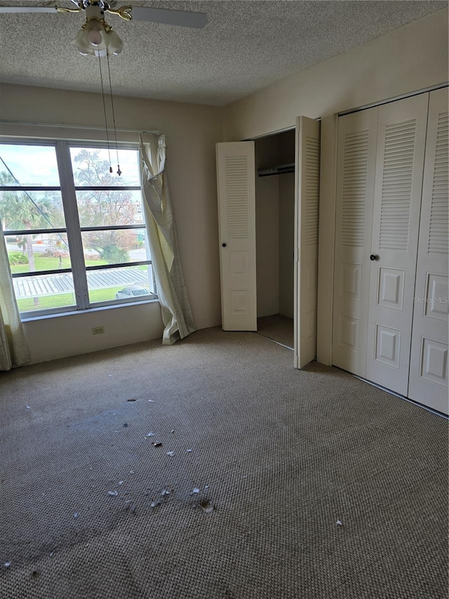 2300 Aaron St Unit 315, Port Charlotte, FL 33952 - unfurnished bedroom featuring multiple closets, carpet floors, a textured ceiling, and a ceiling fan