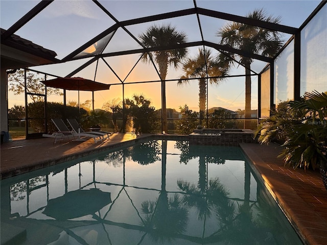 pool at dusk featuring a patio area and glass enclosure