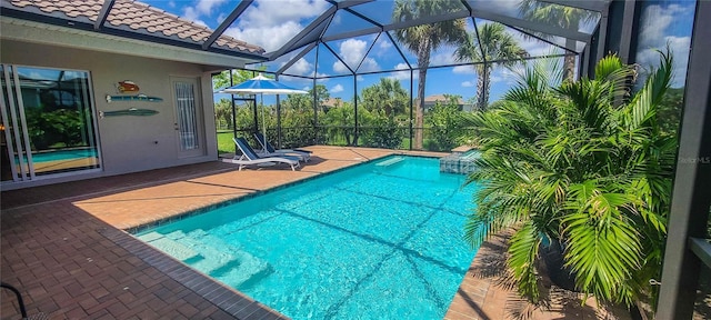 view of swimming pool featuring a patio and glass enclosure