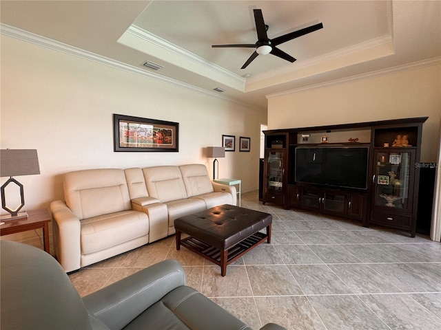 tiled living room with a raised ceiling, ornamental molding, and ceiling fan