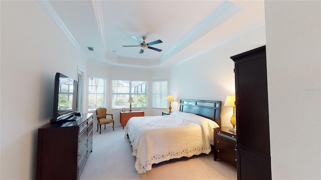 bedroom featuring ornamental molding, light carpet, ceiling fan, and a tray ceiling