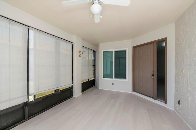 unfurnished sunroom featuring ceiling fan